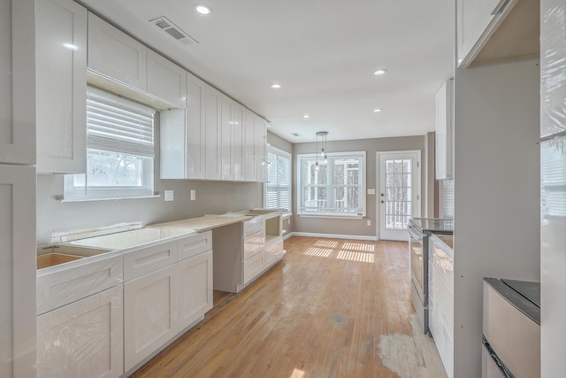 kitchen with visible vents, stainless steel range with electric cooktop, white cabinetry, and light wood-type flooring