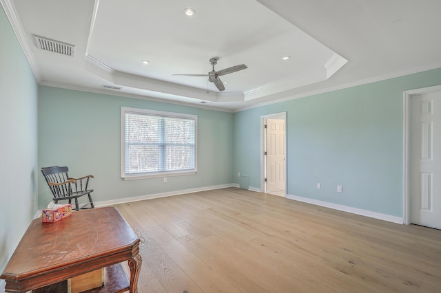 sitting room with a tray ceiling, baseboards, light wood-style floors, and visible vents