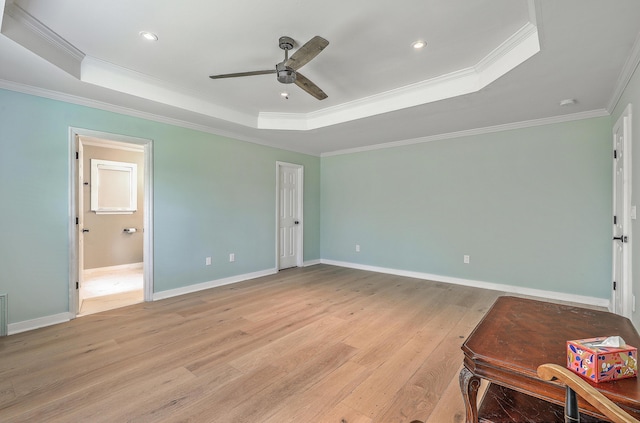 bedroom with a tray ceiling, baseboards, light wood-type flooring, and ornamental molding