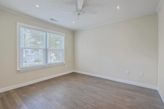 spare room with visible vents, a textured ceiling, wood finished floors, and crown molding