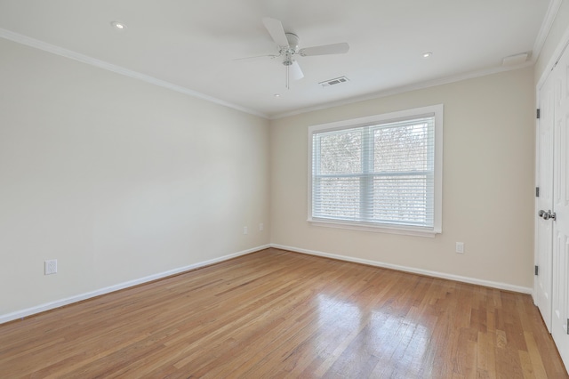 unfurnished room with crown molding, light wood-style floors, visible vents, and baseboards