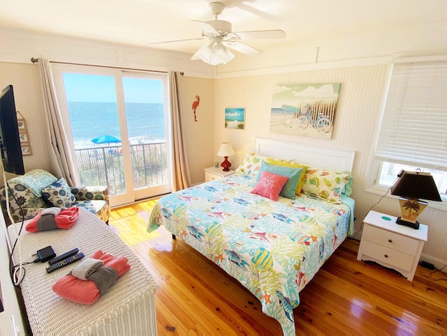 bedroom with access to exterior, wood-type flooring, a water view, and ceiling fan