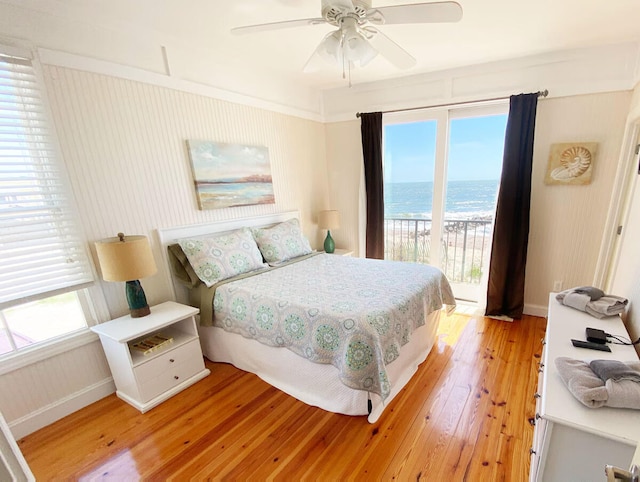 bedroom featuring access to exterior, a water view, ceiling fan, and light hardwood / wood-style floors