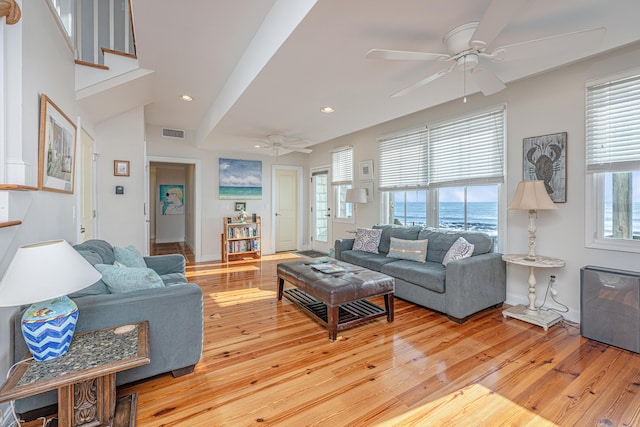 living room featuring vaulted ceiling, a water view, light hardwood / wood-style flooring, and ceiling fan