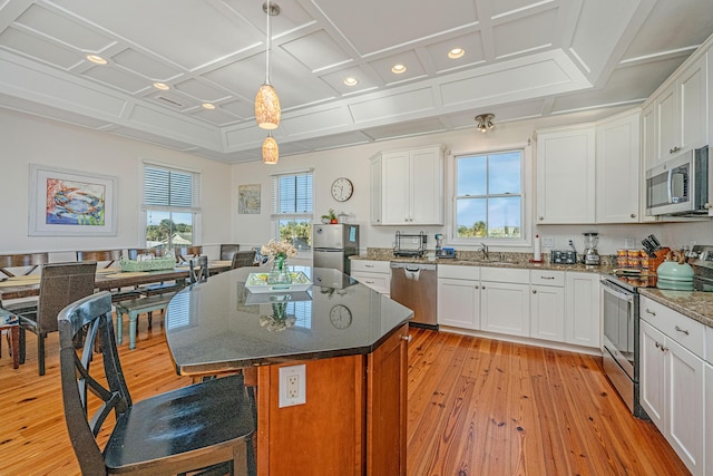 kitchen with white cabinets, stainless steel appliances, hanging light fixtures, and coffered ceiling