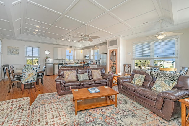 living room with light hardwood / wood-style floors, ceiling fan, and coffered ceiling