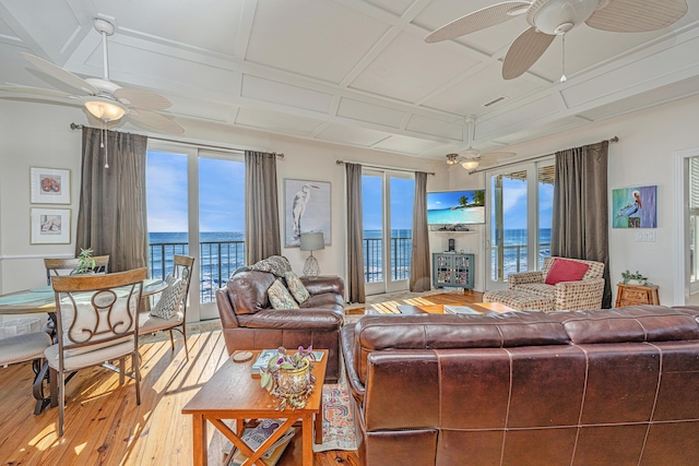 living room featuring hardwood / wood-style floors, a water view, a wealth of natural light, and coffered ceiling