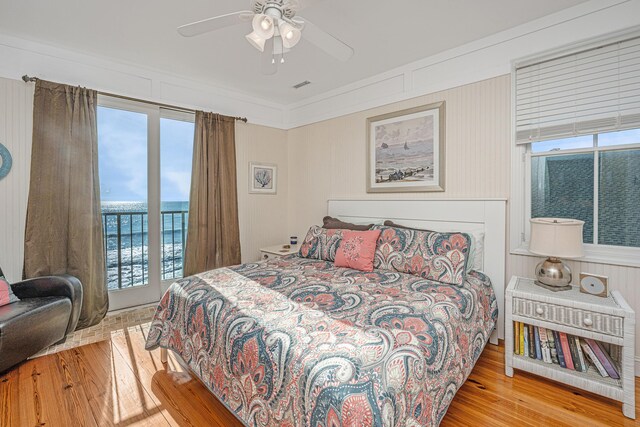 bedroom with light wood-type flooring, a water view, ceiling fan, and ornamental molding