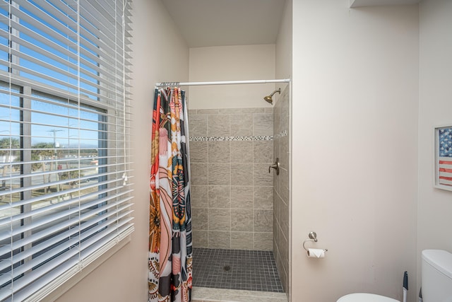 bathroom with a shower with shower curtain and toilet