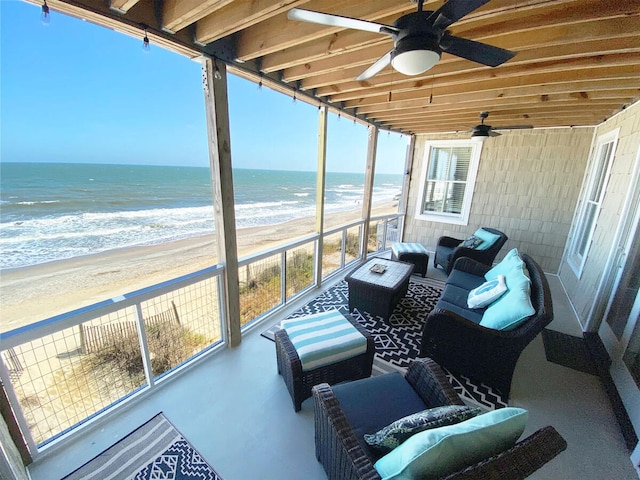 sunroom featuring plenty of natural light, a water view, and a beach view