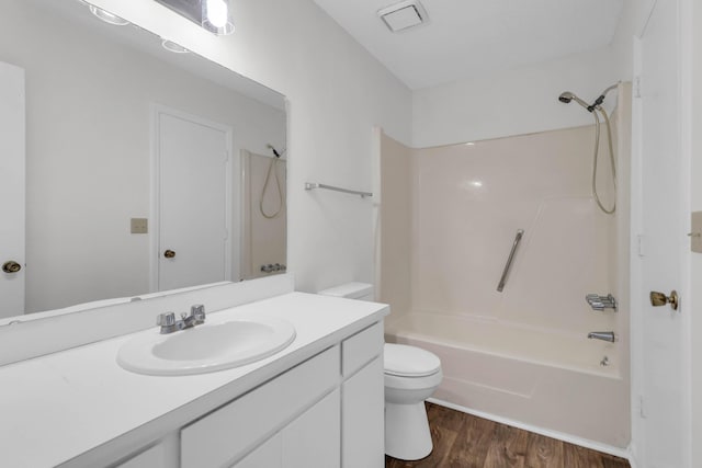 bathroom with toilet,  shower combination, wood finished floors, and vanity