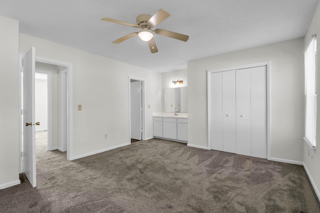 unfurnished bedroom featuring baseboards, ensuite bath, ceiling fan, carpet, and a closet