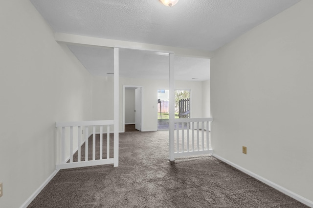 carpeted empty room featuring a textured ceiling and baseboards