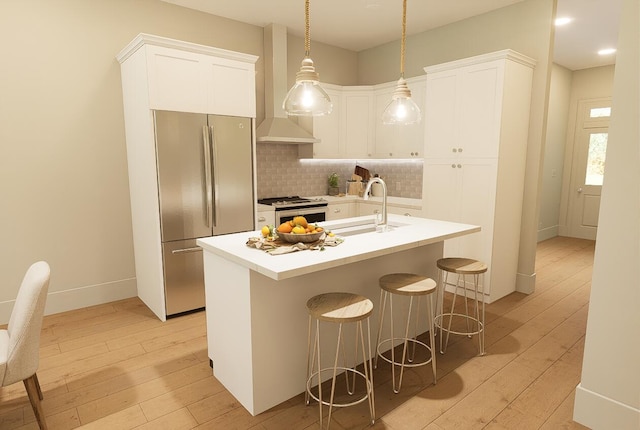 kitchen featuring a center island with sink, light hardwood / wood-style flooring, stainless steel appliances, and decorative light fixtures