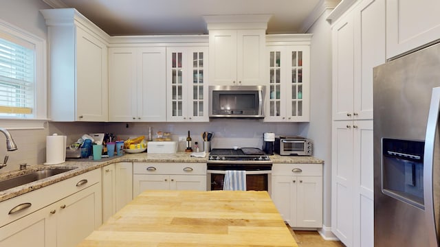 kitchen featuring sink, stainless steel appliances, white cabinets, and light stone countertops