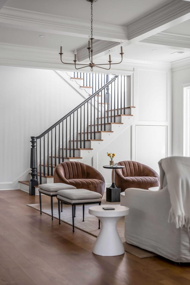 staircase featuring hardwood / wood-style flooring, ornamental molding, beam ceiling, and an inviting chandelier