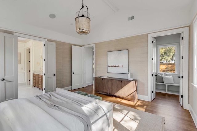 bedroom featuring vaulted ceiling, wood-type flooring, and connected bathroom