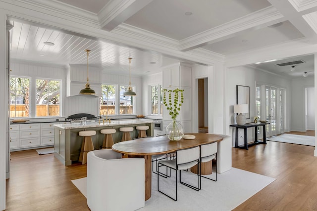 dining room featuring crown molding, beamed ceiling, and light wood-type flooring