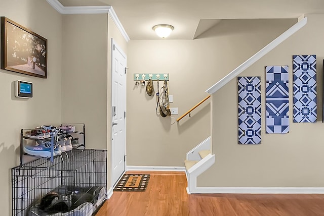 entrance foyer featuring ornamental molding, baseboards, wood finished floors, and stairway