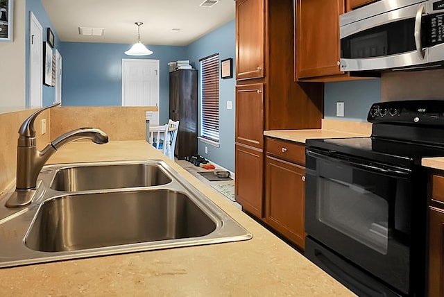 kitchen featuring a sink, stainless steel microwave, electric range, brown cabinetry, and light countertops