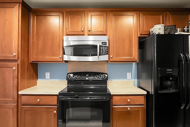 kitchen featuring light countertops, brown cabinetry, and black appliances
