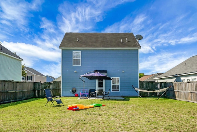 rear view of property featuring a yard, a patio, and a fenced backyard
