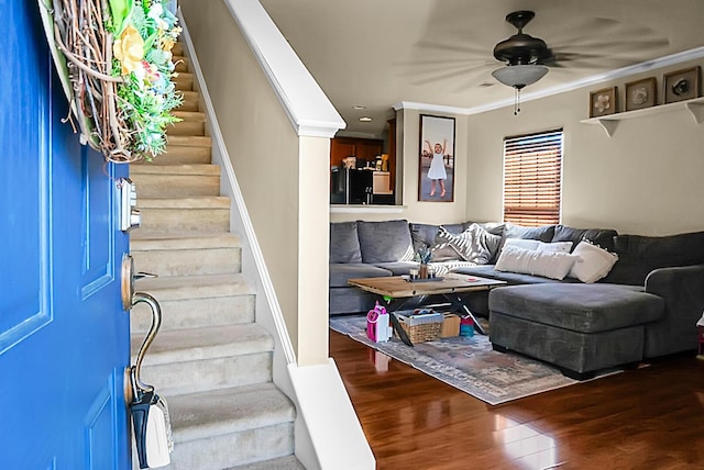 interior space with wood finished floors, a ceiling fan, stairs, and ornamental molding