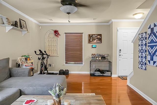 living room featuring light wood-type flooring, a ceiling fan, baseboards, and ornamental molding