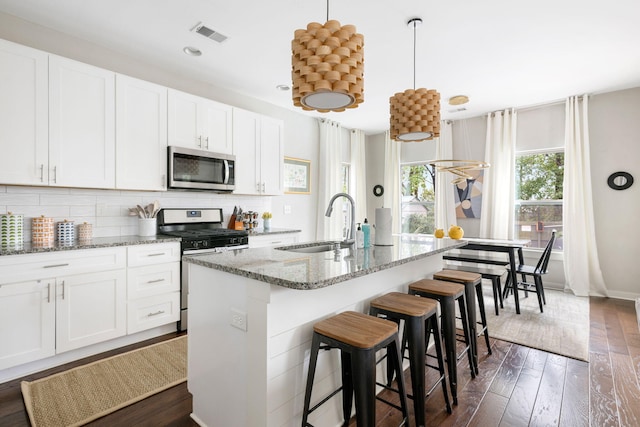 kitchen with visible vents, an island with sink, a sink, backsplash, and stainless steel appliances