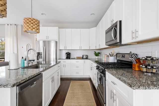 kitchen with dark wood-style flooring, backsplash, appliances with stainless steel finishes, and a sink