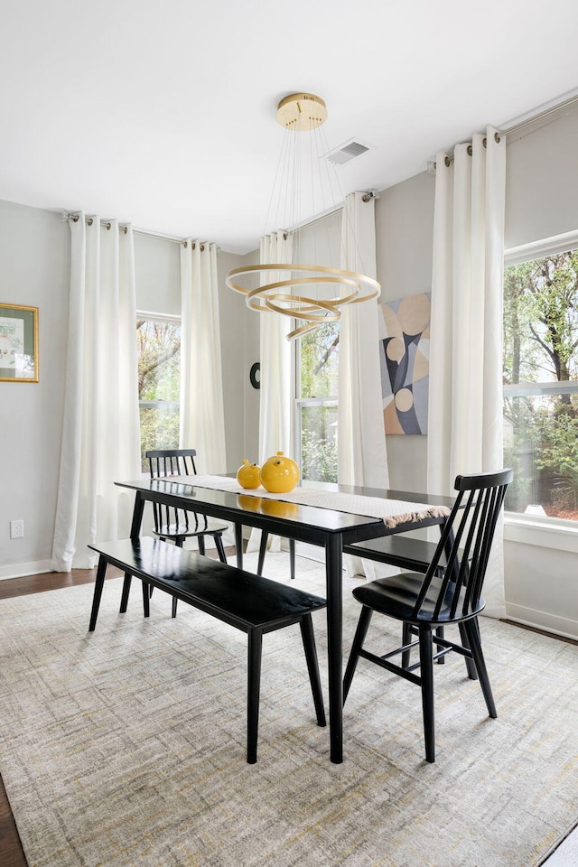 dining area with visible vents, an inviting chandelier, baseboards, and wood finished floors