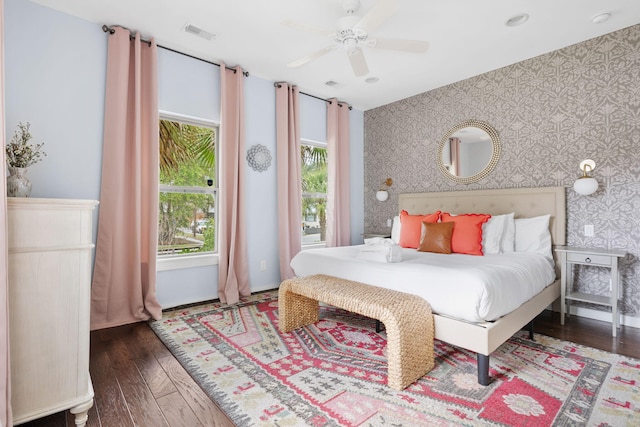 bedroom with visible vents, a ceiling fan, wood finished floors, wallpapered walls, and baseboards