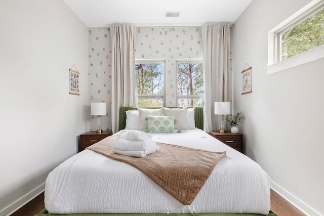 bedroom with visible vents, baseboards, and wood finished floors