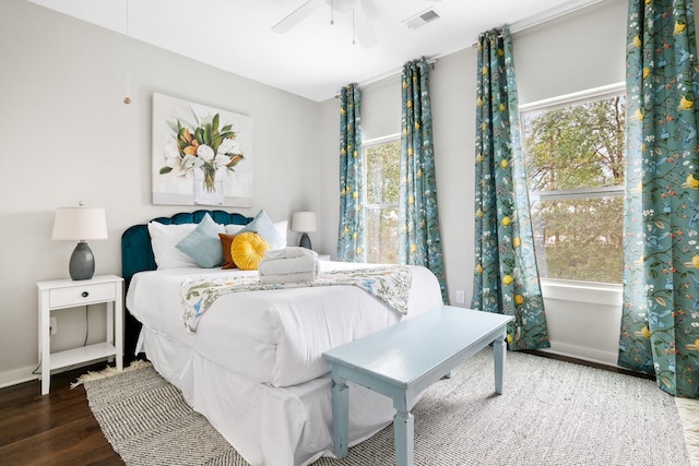 bedroom with visible vents, baseboards, wood finished floors, and a ceiling fan