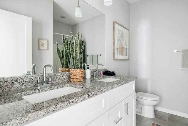 full bath featuring double vanity, toilet, baseboards, and a sink