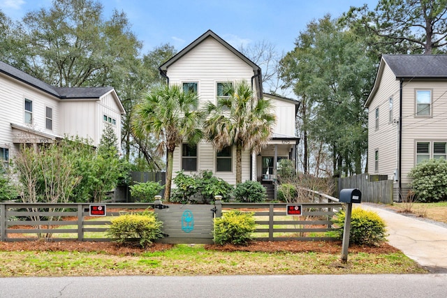 view of front of property with concrete driveway, a gate, and a fenced front yard