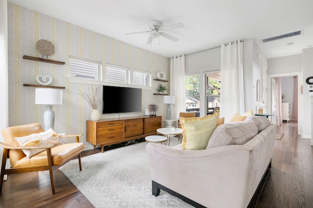 living room with wallpapered walls, hardwood / wood-style flooring, visible vents, and ceiling fan