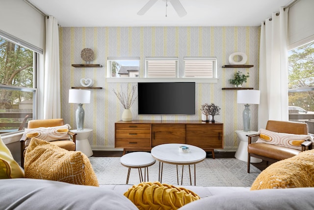 living area with baseboards, a healthy amount of sunlight, a ceiling fan, and wallpapered walls