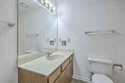 bathroom with vanity, toilet, and baseboards