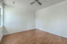 spare room featuring a ceiling fan, wood finished floors, baseboards, and a healthy amount of sunlight