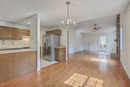 kitchen featuring brown cabinets, wood finished floors, light countertops, and freestanding refrigerator