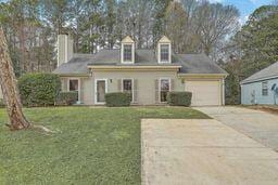 cape cod home with concrete driveway, a garage, and a front lawn