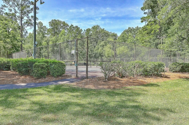 view of sport court with a yard, fence, and a gate