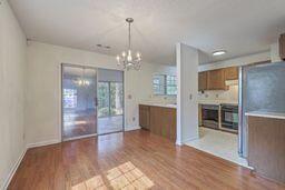 interior space with decorative light fixtures, light countertops, brown cabinets, an inviting chandelier, and wood finished floors