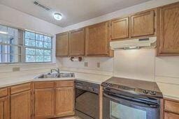 kitchen featuring dishwashing machine, visible vents, a sink, black electric range, and under cabinet range hood