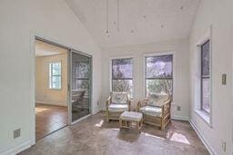 living area featuring lofted ceiling and baseboards