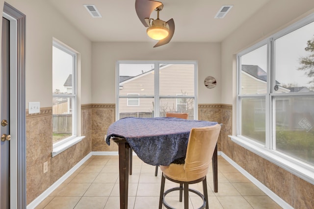 dining space featuring light tile patterned floors, visible vents, and wainscoting