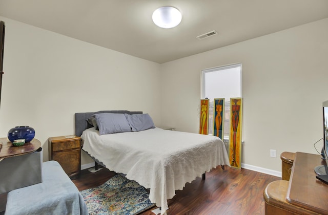 bedroom with visible vents, baseboards, and wood finished floors