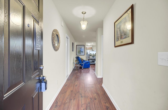 corridor with dark wood-style floors and baseboards