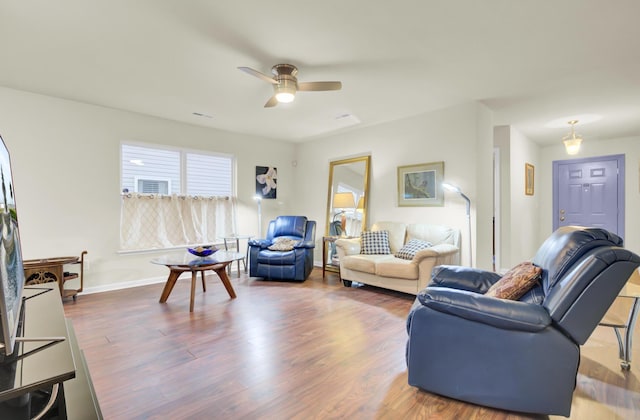 living room with ceiling fan, baseboards, and wood finished floors